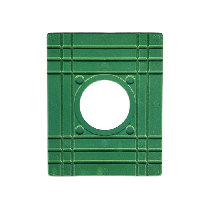 The backside of a green, square-shaped plastic plate with a circular hole in the center. Raised grid-like reinforcement patterns provide structural support.