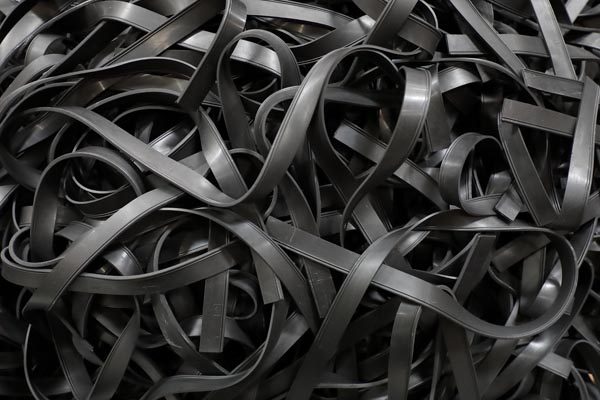 A tangled mass of black squeegee rubber blades with a matte finish, scattered haphazardly to show volume and texture. The image captures the high-quality rubber material and the flexibility of the blades used for window cleaning.