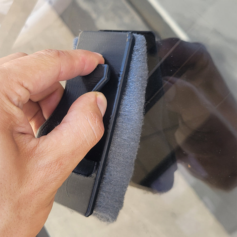 Hand holding a mag scrubber on a window cleaning task.