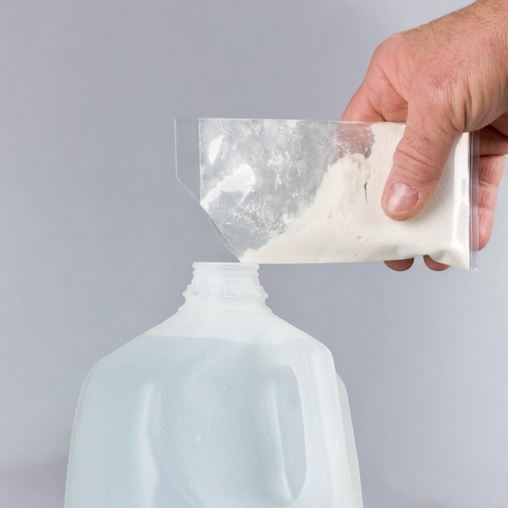 A hand pouring the RO Protect powder from a small clear plastic bag into an empty gallon container, showing the preparation process for use.