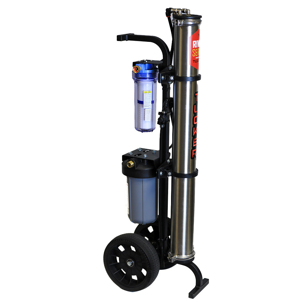 A portable stainless steel 3-stage RO/DI water filtration system on wheels, featuring a vertical design with a carbon pre-filter housed in a clear blue cylinder at the top, a reverse osmosis membrane in the middle, and a refillable DI filter at the bottom. The system has a black powder-coated steel frame with a curved handle, two large black pneumatic tires for mobility, and a kickstand for stability. The brand 'TUCKER' is prominently displayed on the central steel cylinder.