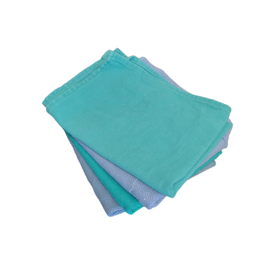 A neatly folded set of teal and grey reclaimed surgical towels, with a focus on the clean fold lines and color contrast.