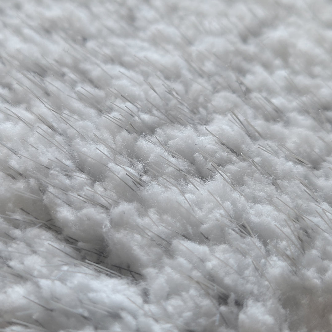 Close-up view of a white microfiber pad with interspersed nylon bristles. The texture appears dense and fluffy, with the thin bristles evenly distributed throughout the pad.