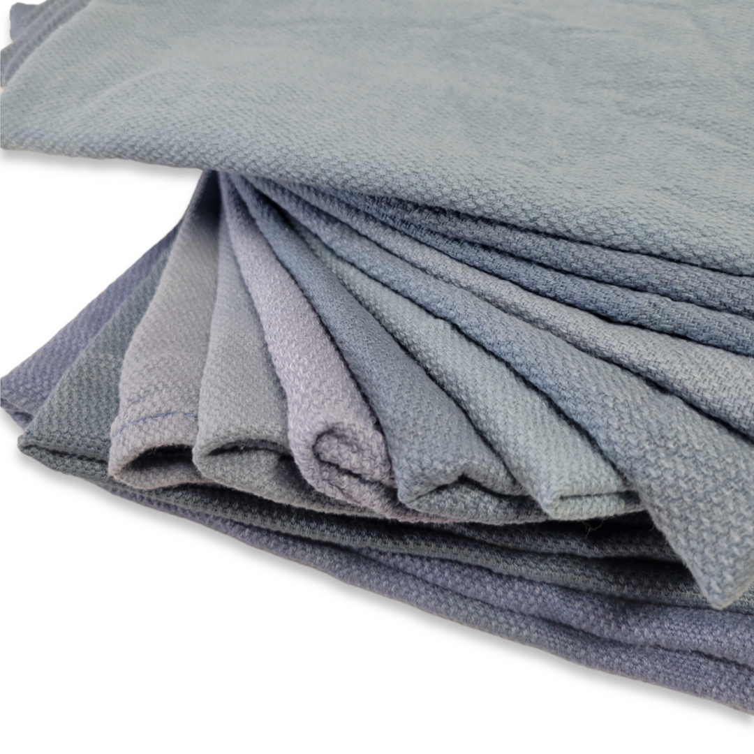 A close-up view of assorted grey and blue reclaimed surgical towels, emphasizing the weave and fabric quality.